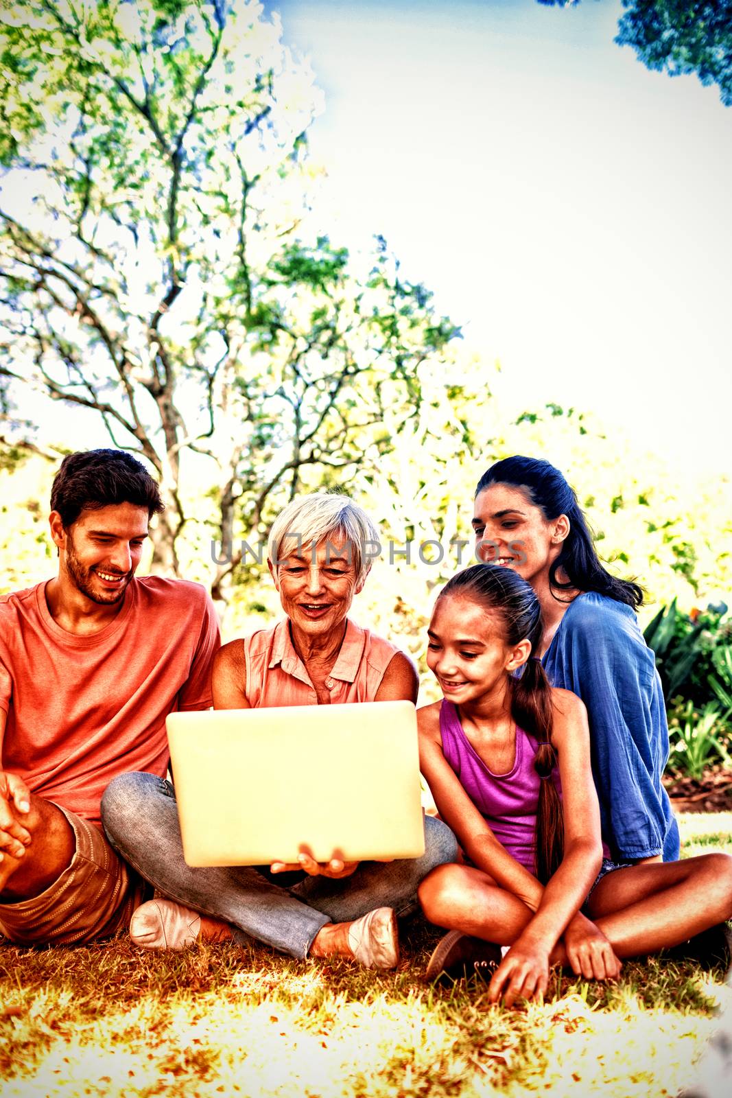 Smiling family using laptop in the park