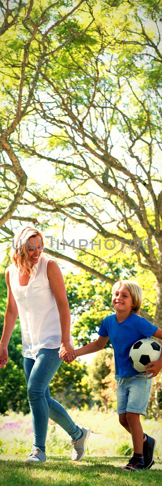 Mother and son walking in the park with football on a sunny day