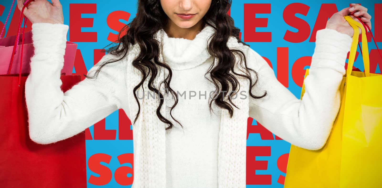 Woman with christmas hat holding colored shopping bags against blue background