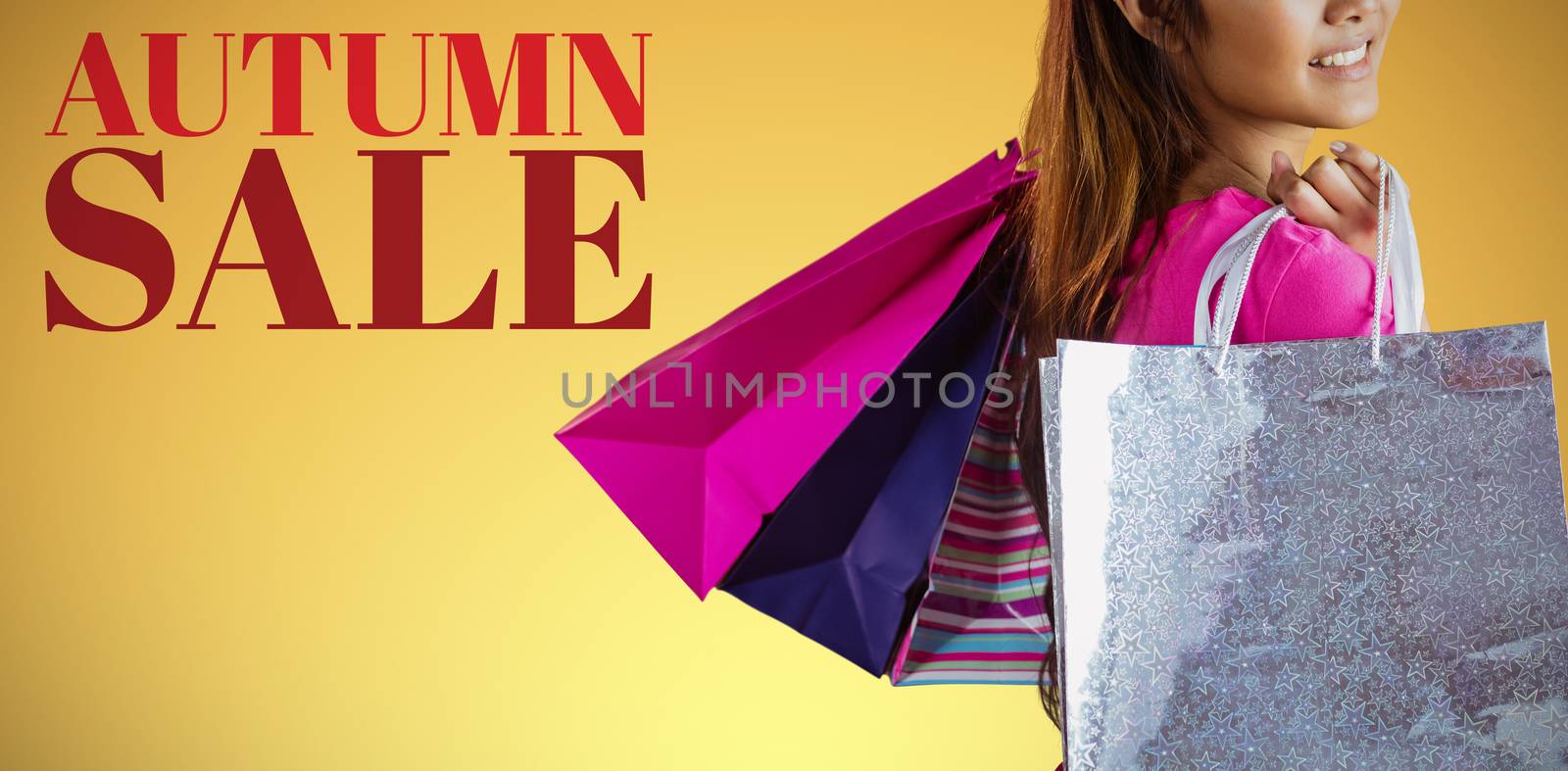 Smiling asian woman with shopping bags against abstract yellow background