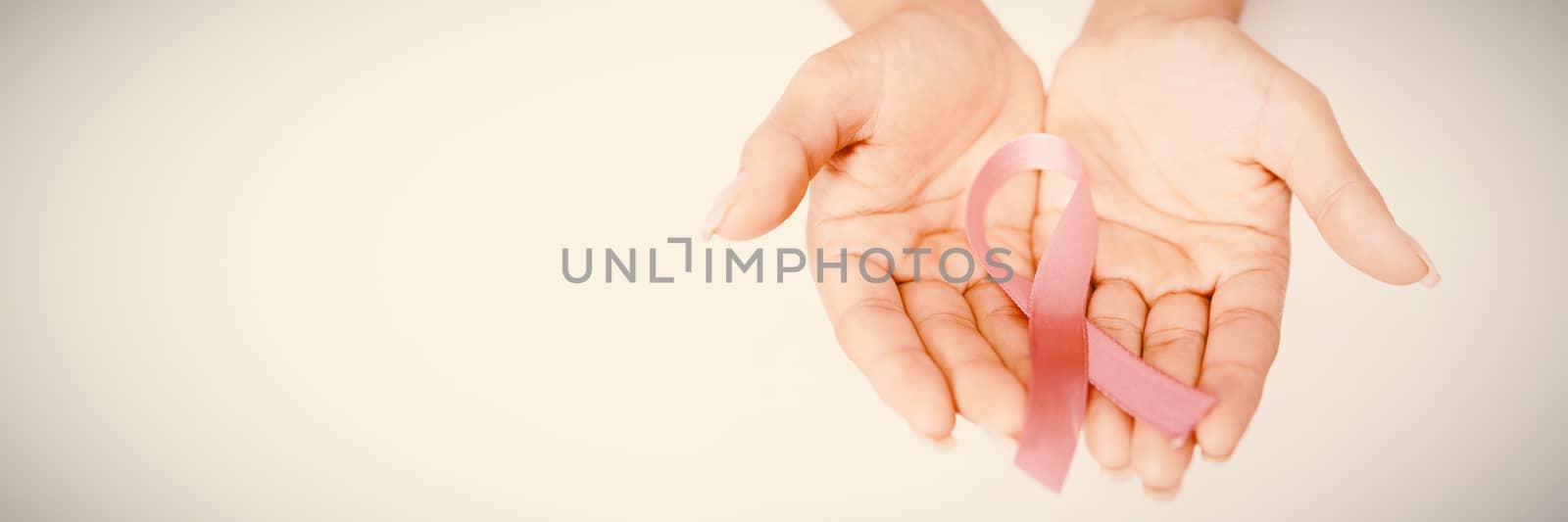 Two hands showing pink ribbon against breast cancer against white background