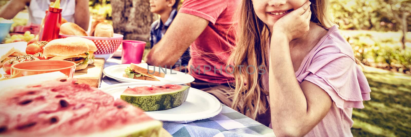 Girl sitting at the table with having meal whith her family in park by Wavebreakmedia