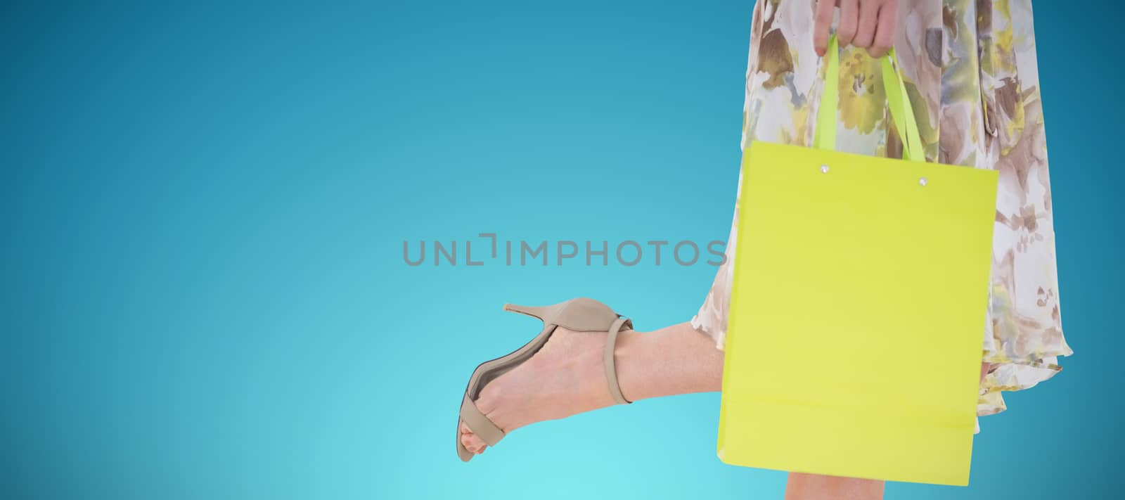 Elegant woman holding shopping bag against abstract blue background