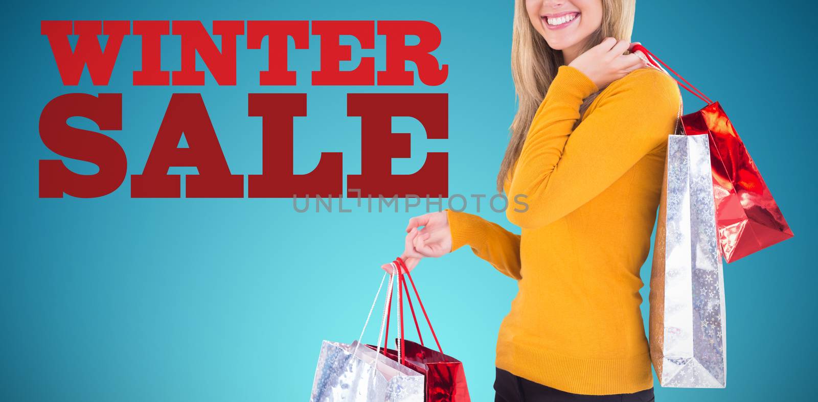 Stylish blonde smiling with shopping bags against abstract blue background