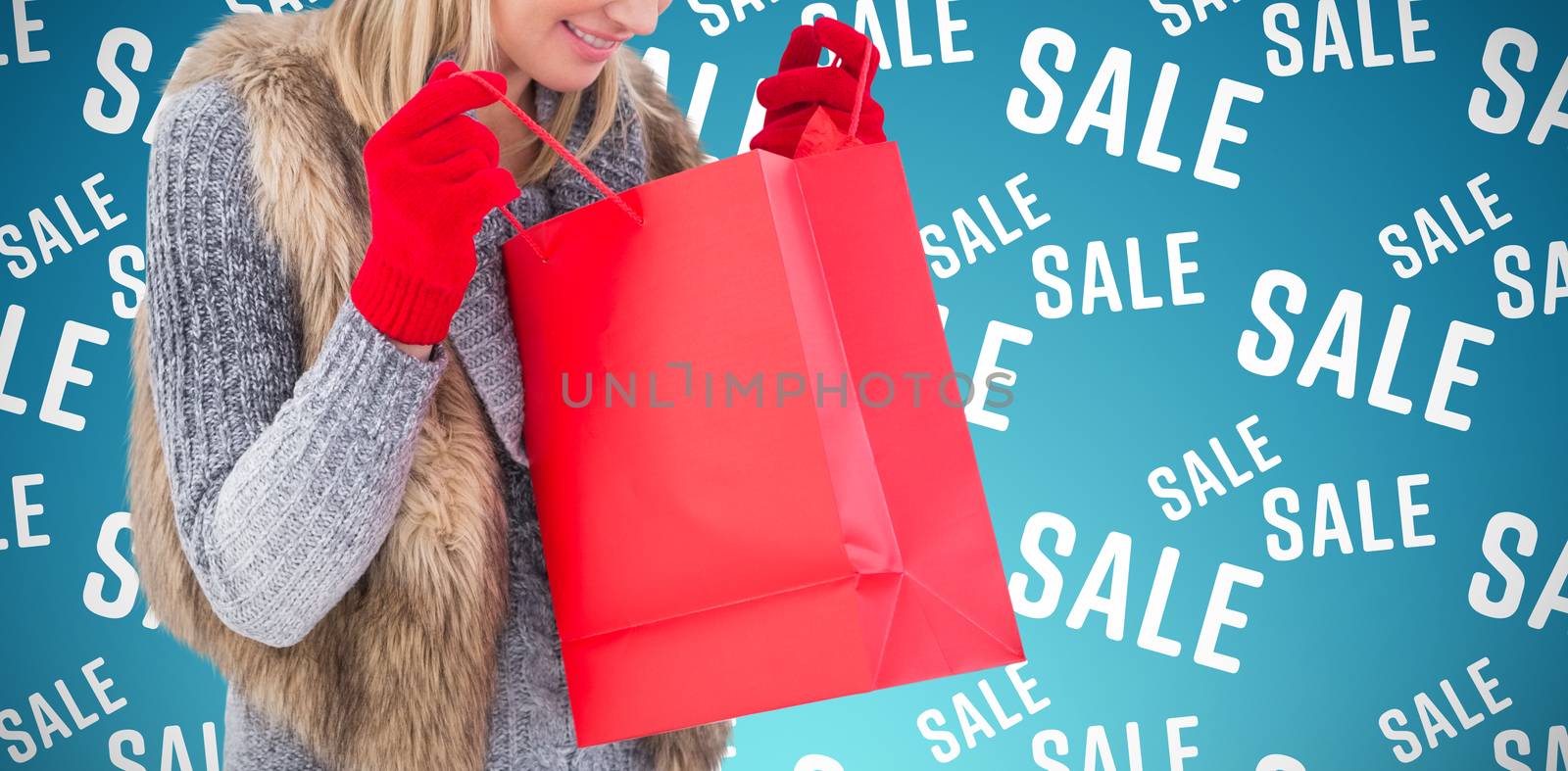 Blonde in winter clothes looking in shopping bag against abstract blue background
