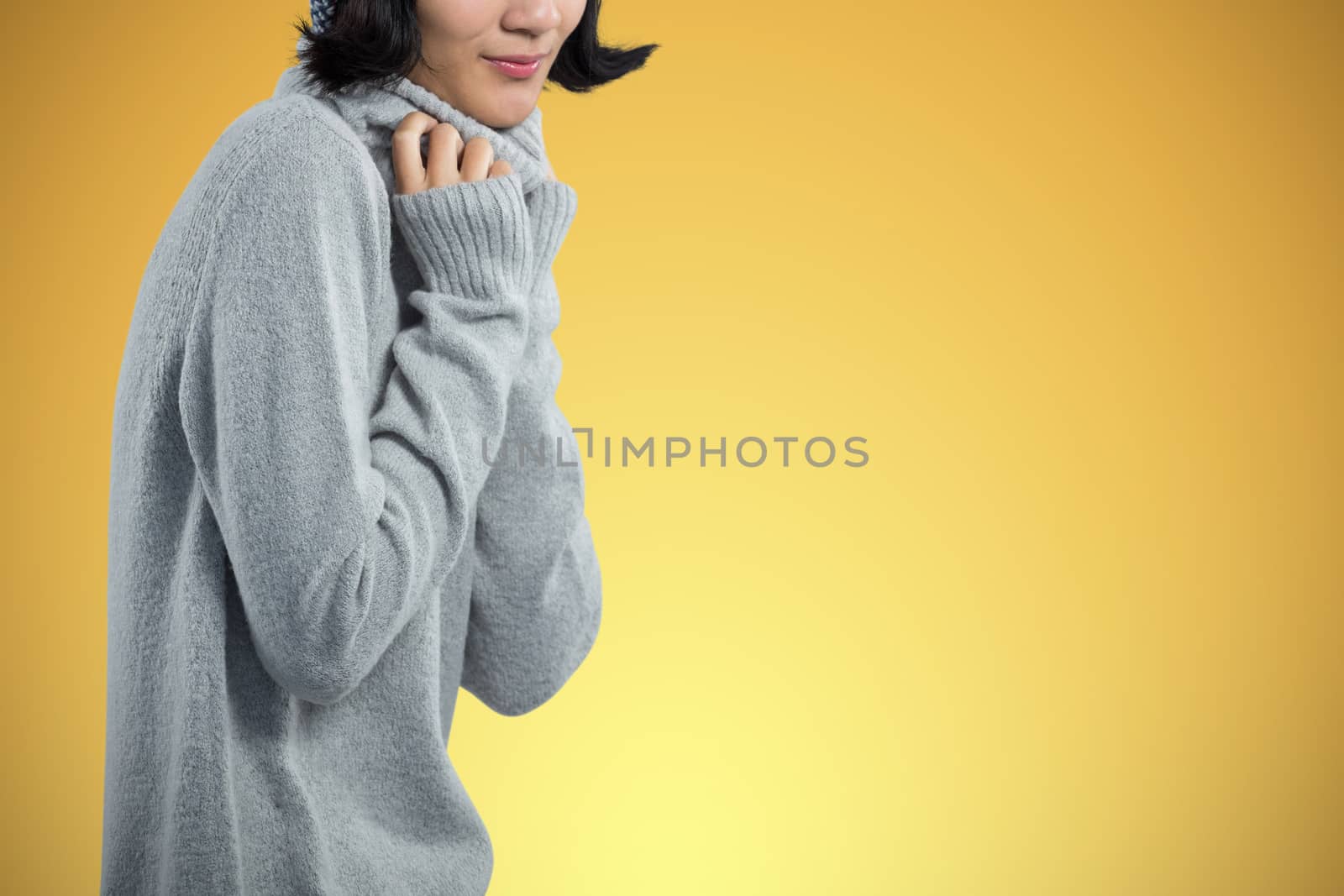 Woman in winter clothing posing against white background against abstract yellow background