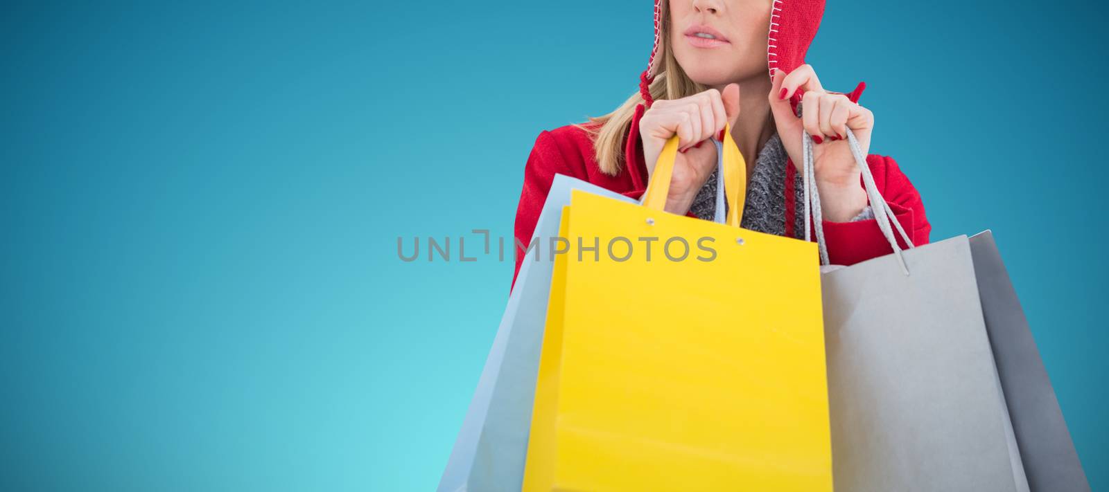 Blonde in winter clothes holding shopping bags against abstract blue background