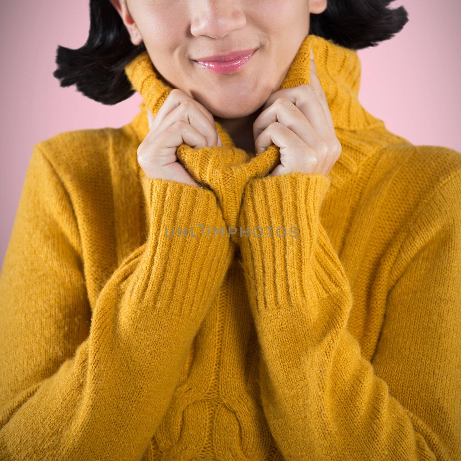 Woman in winter clothing posing against white background against pink background 
