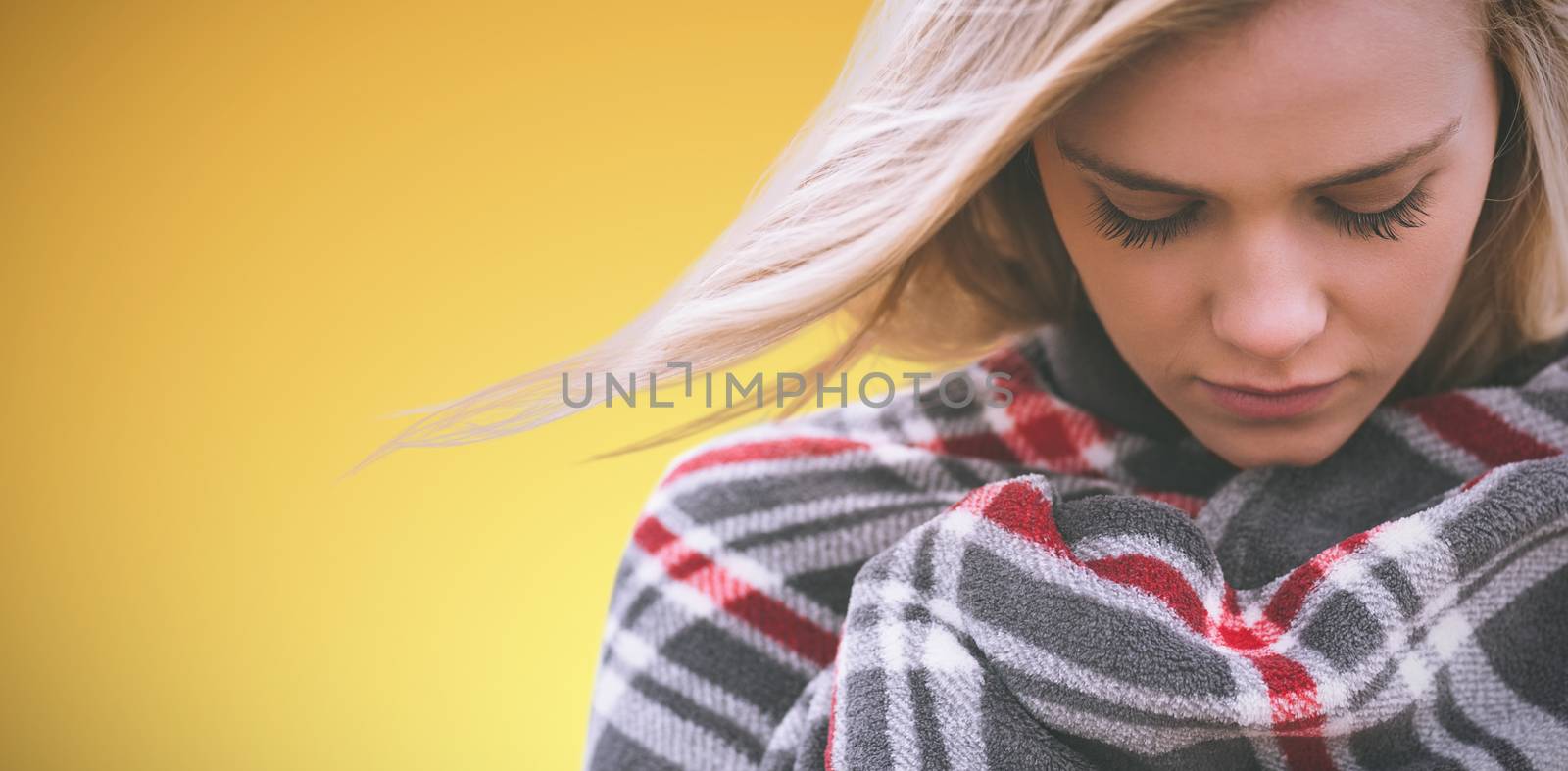 Close up of a woman wraped in a blanket against abstract yellow background