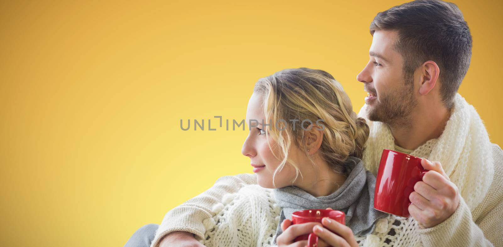  Cheerful couple in winter clothing holding cups against window against abstract yellow background