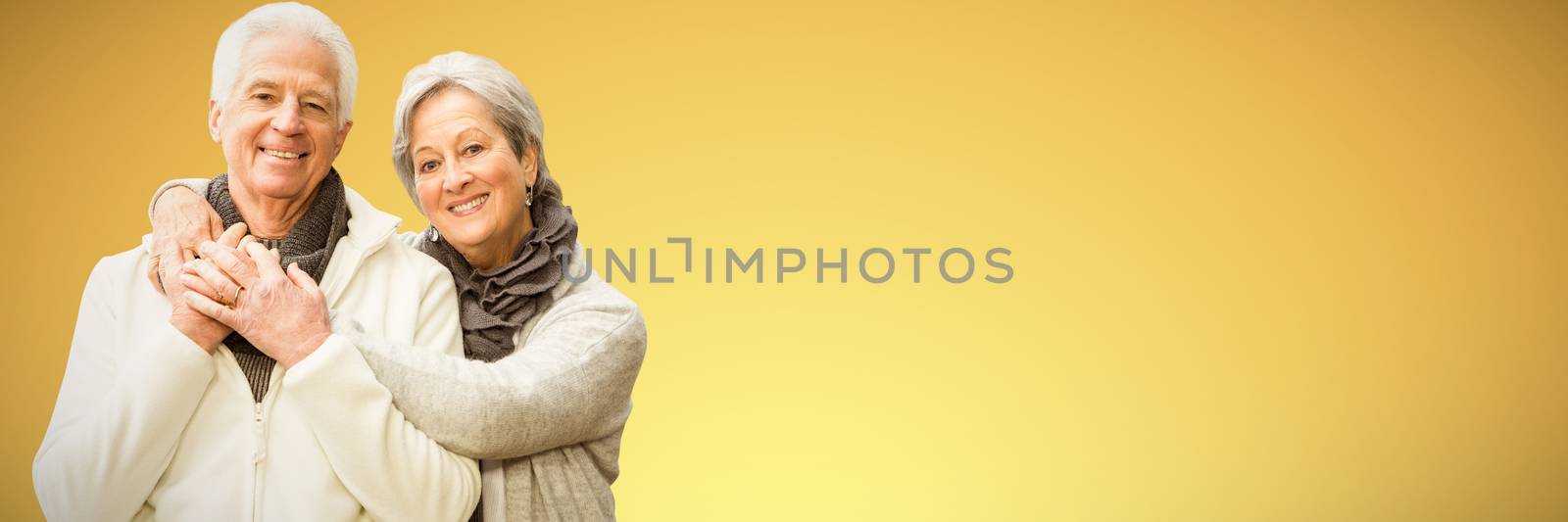  Senior couple embracing each other at home against abstract yellow background