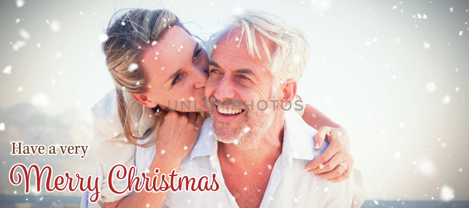 Man giving his smiling wife a piggy back at the beach against christmas card