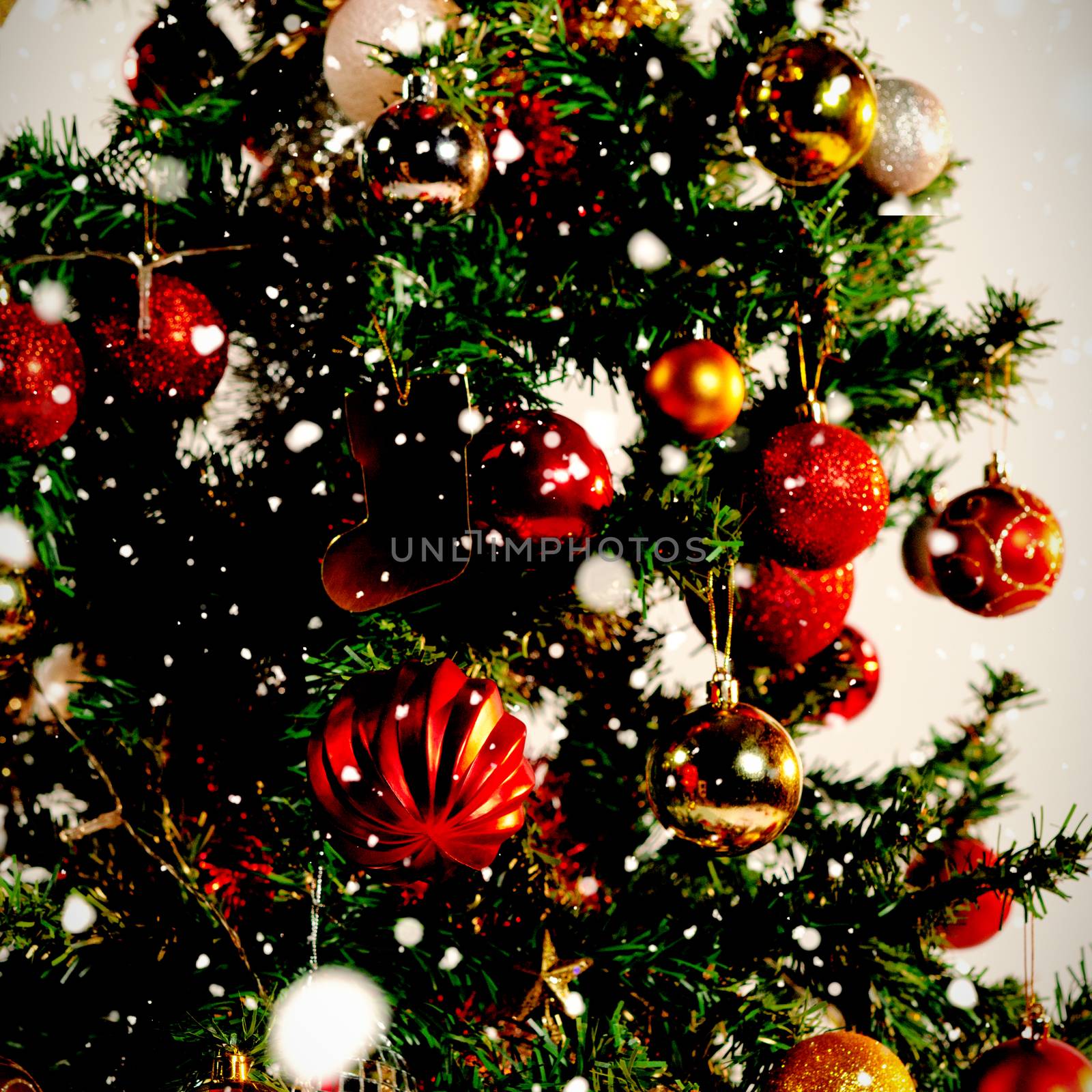 Snow falling against christmas balls on a pine