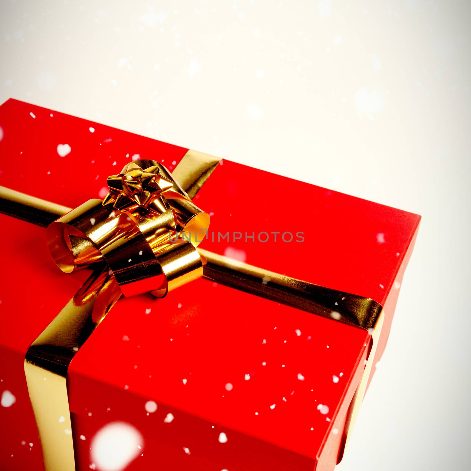 Snow falling against christmas gift with golden bow
