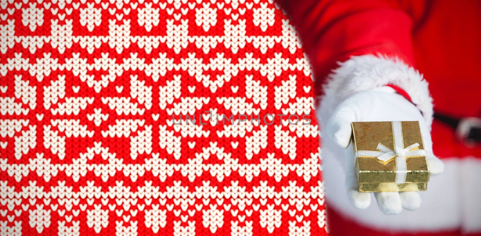Santa claus holding gift box in hand against christmas jumper pattern
