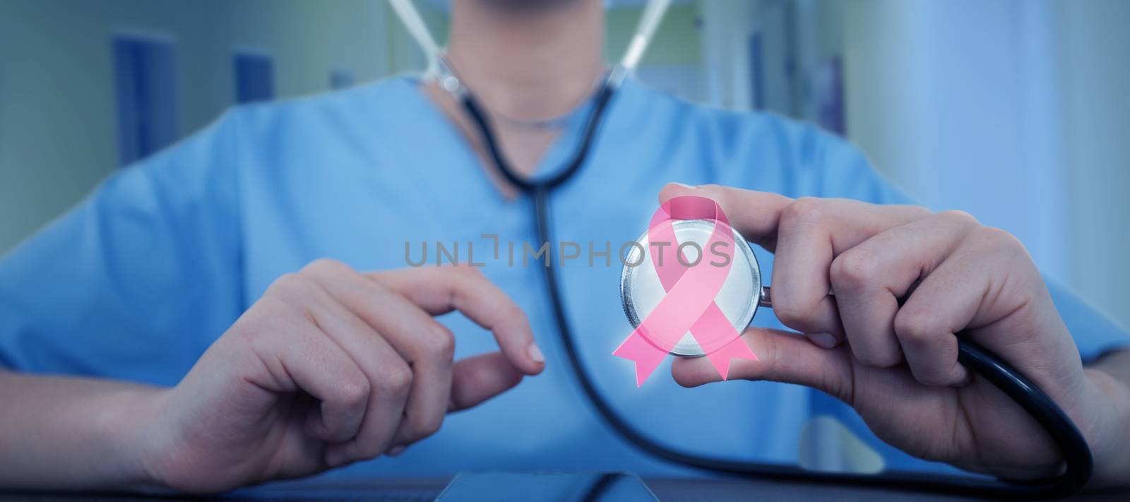 Mid-section of female doctor examining digital tablet with stethoscope against doctor and nurse standing at corridor