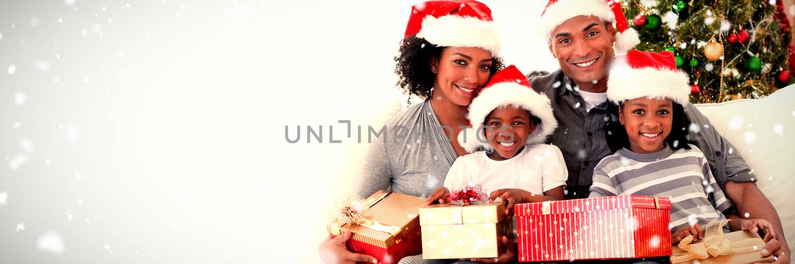 Family holding Christmas presents against snow falling