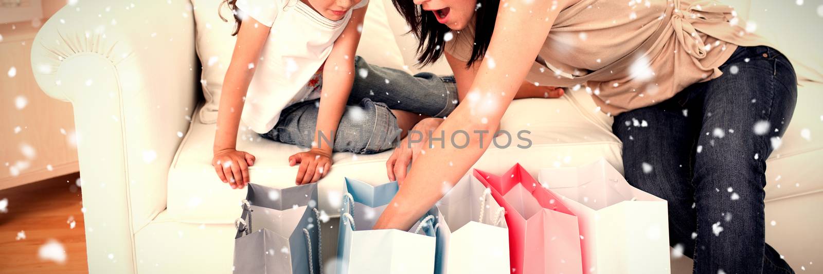 Snow falling against mother and daughter unpacking shopping bags 