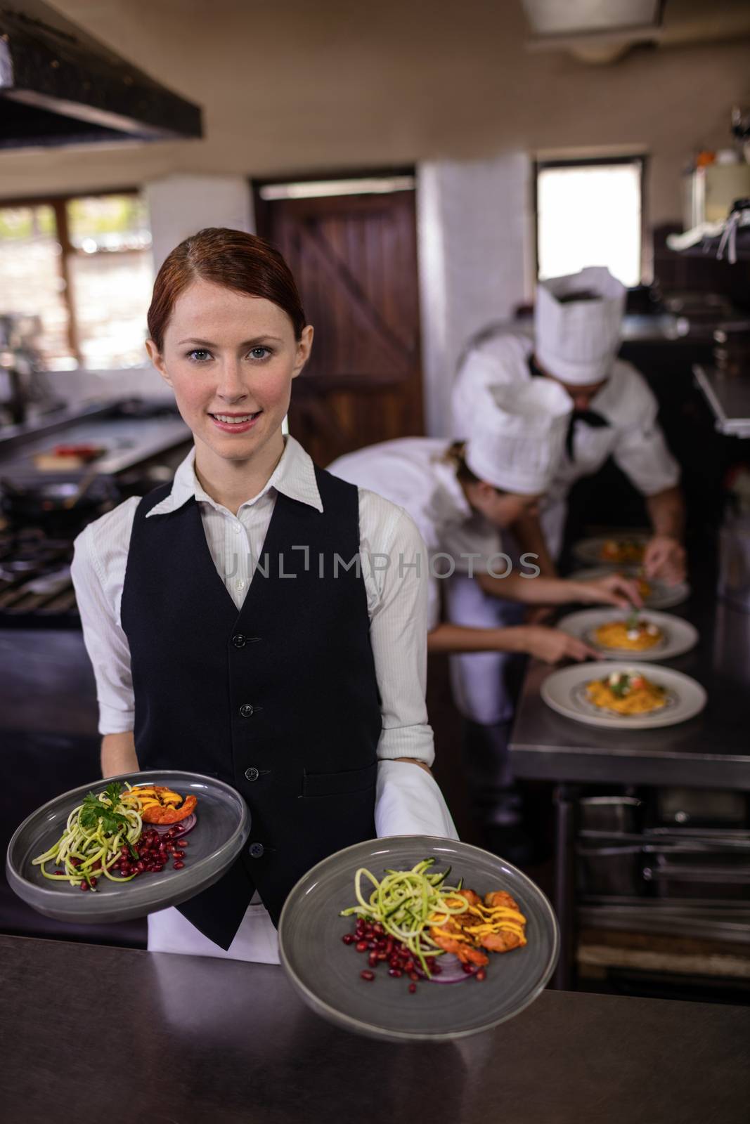 Female waitress holding plates with food in kitchen by Wavebreakmedia