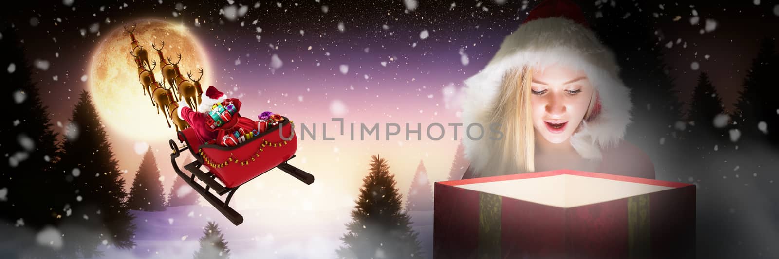 Composite image of festive blonde looking into glowing gift by Wavebreakmedia