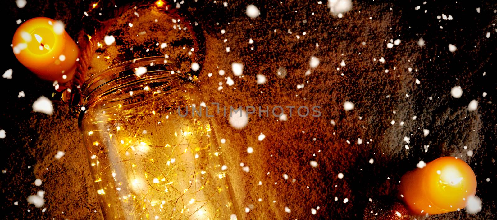 Snow falling against yellow candles and smooth christmas lights