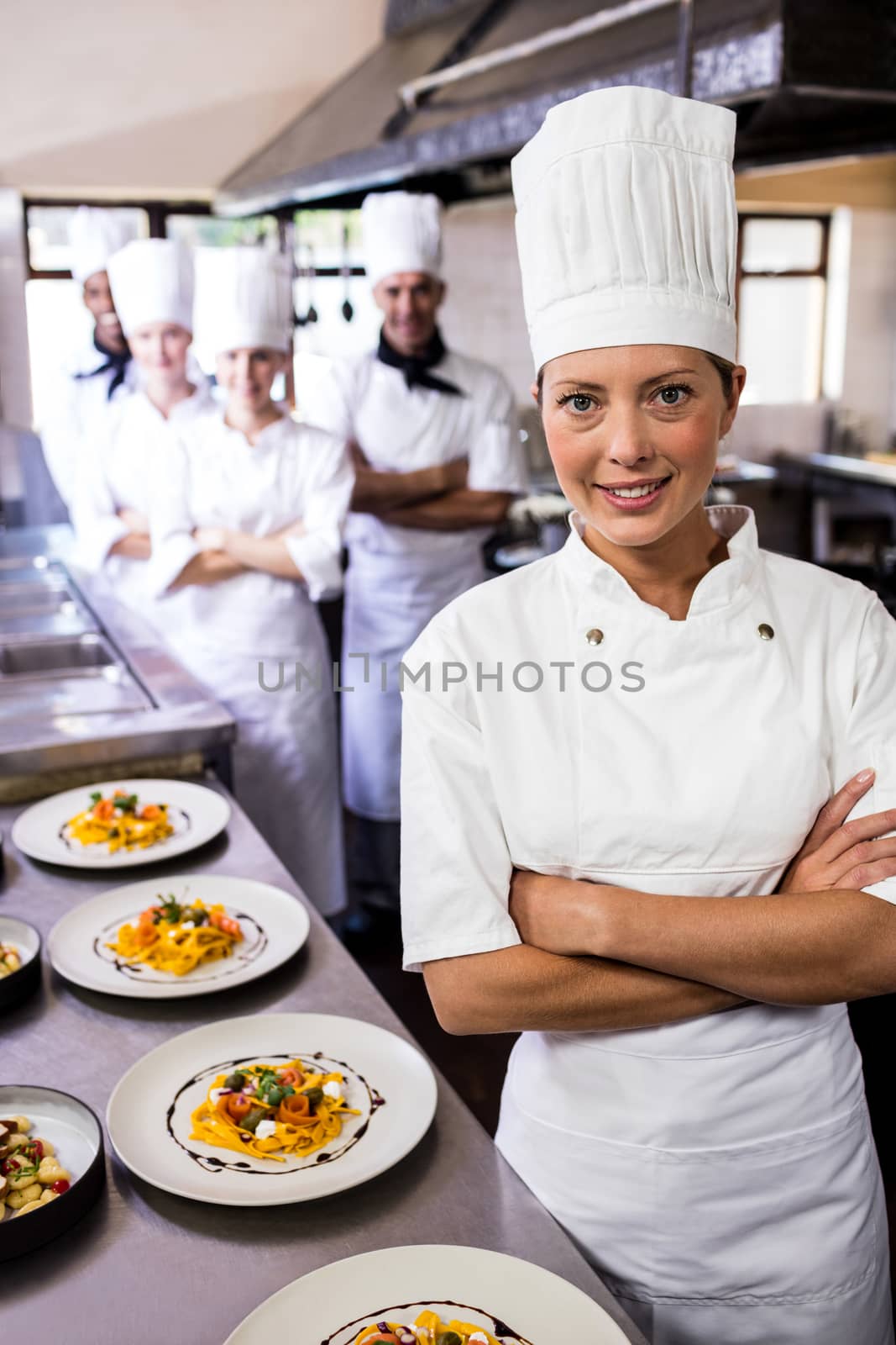 Female chef standing with arms crossed in kitchen by Wavebreakmedia