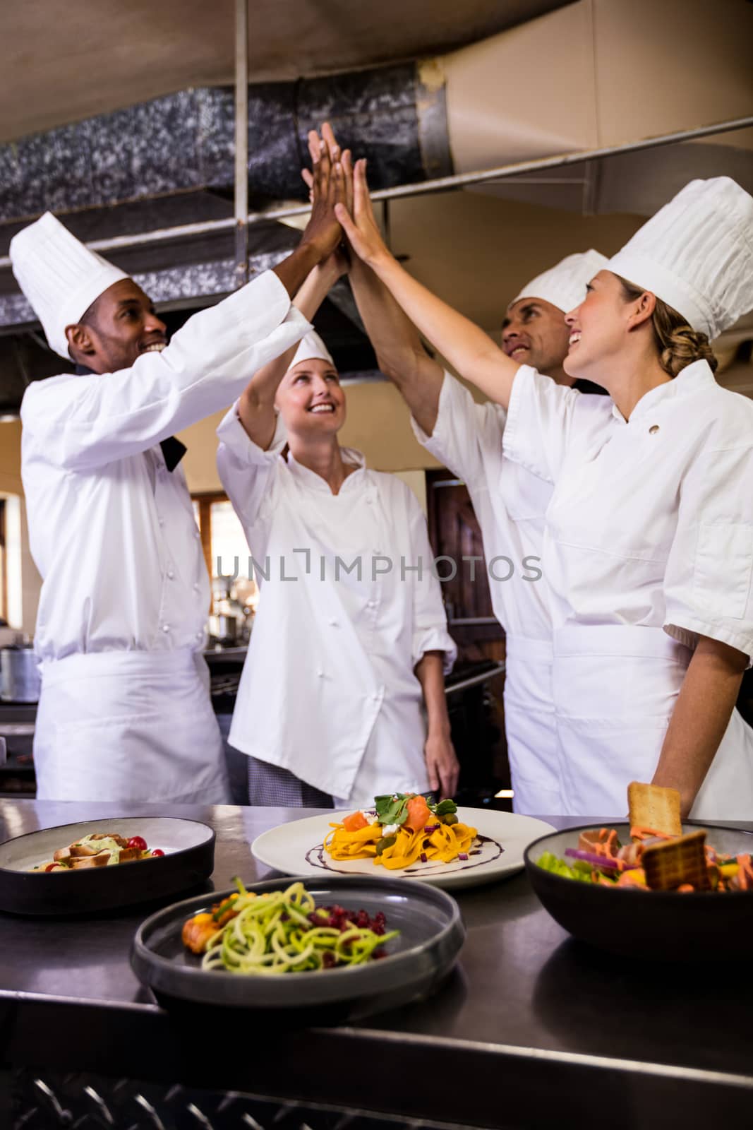 Group of chefs formig hands stack in kitchen at hotel