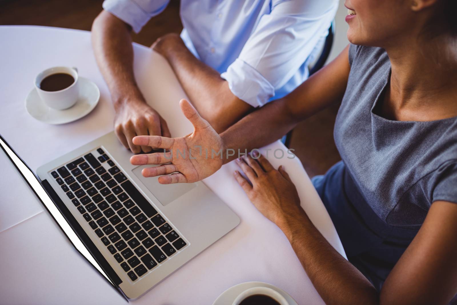 Mid section of business people discussing on laptop in restaurant