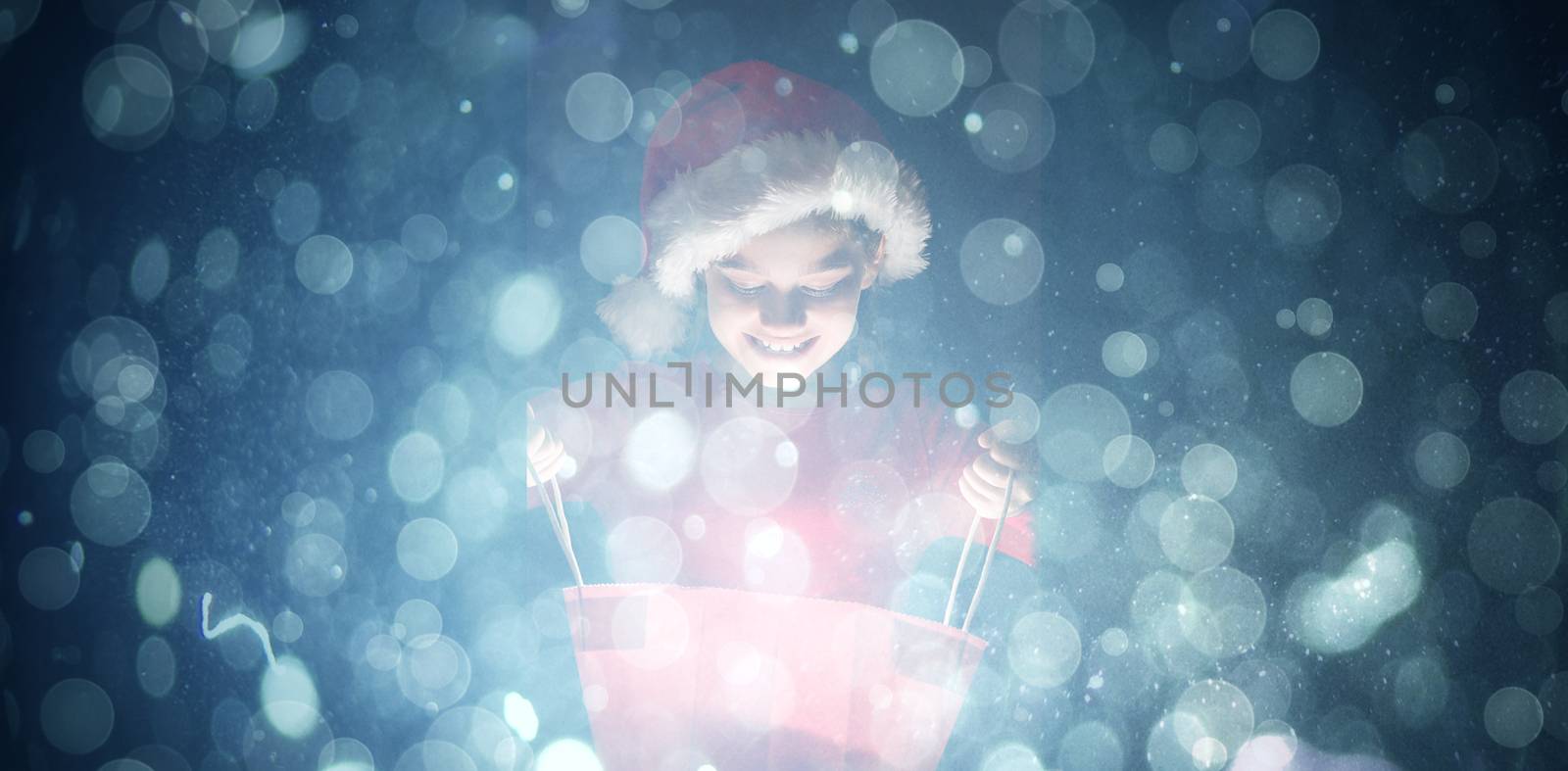 Little girl opening a magical christmas gift against blue abstract light spot design