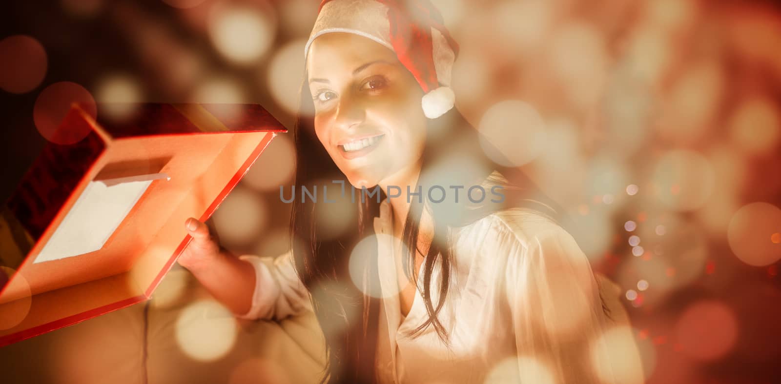 Festive brunette opening a glowing christmas gift against light circles on black background