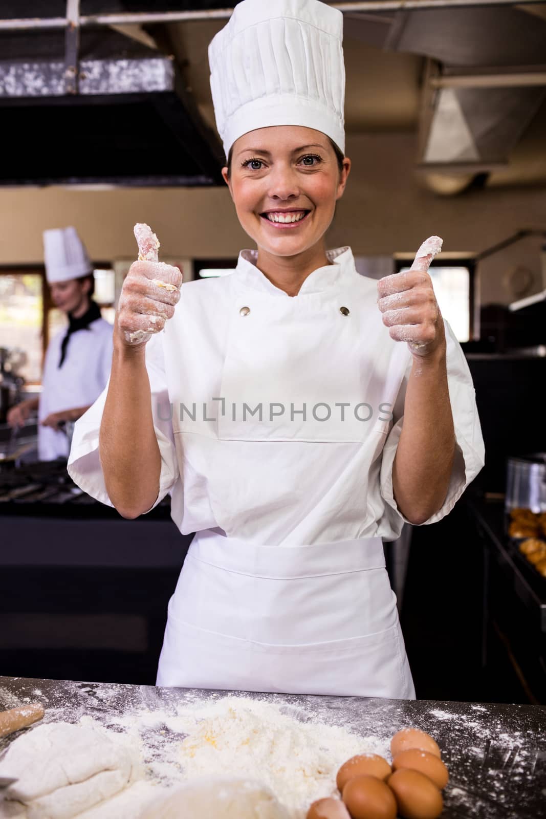 Female chef showing thumbs up in kitchen at hotel