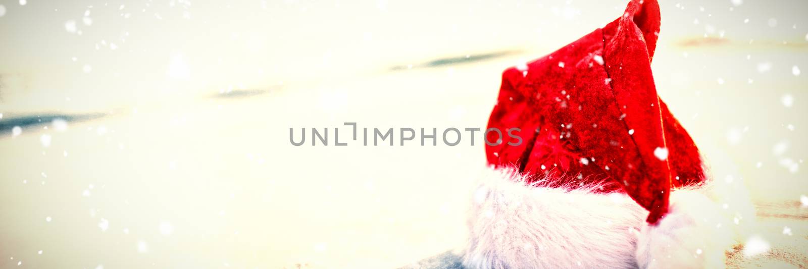 Snow falling against santa hat on the beach 