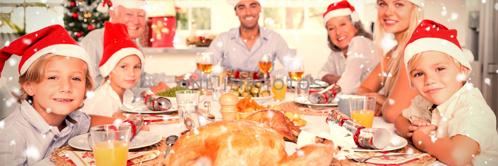 Composite image of happy family wearing santa hats around the dinner table by Wavebreakmedia