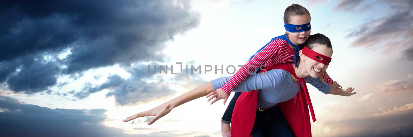 Mother and daughter pretending to be superhero against cloudy sky