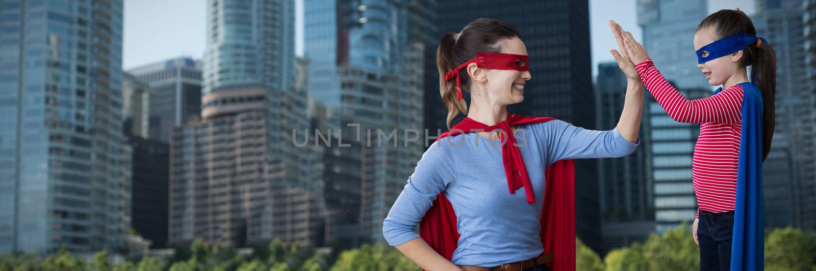 Mother and daughter pretending to be superhero against city