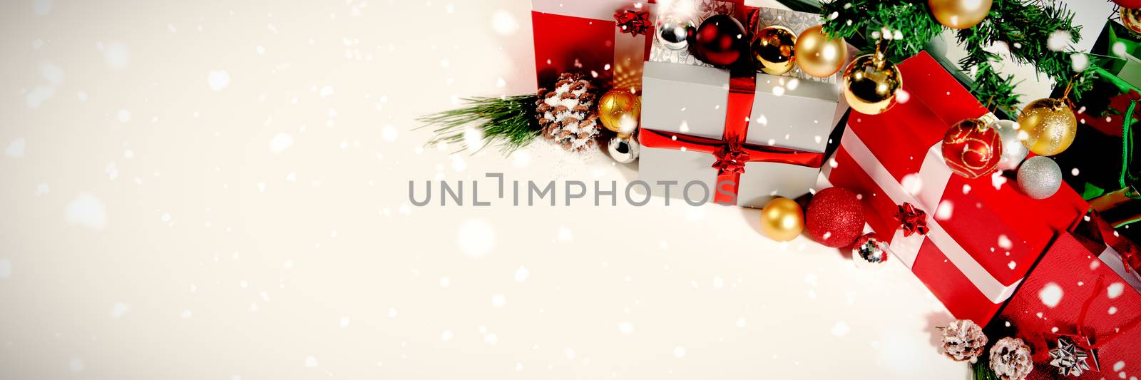 Snow falling against christmas gift and pine cone under the tree