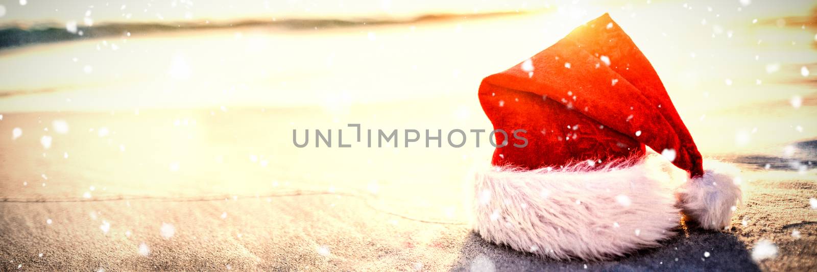 Snow falling against santa hat on the beach 