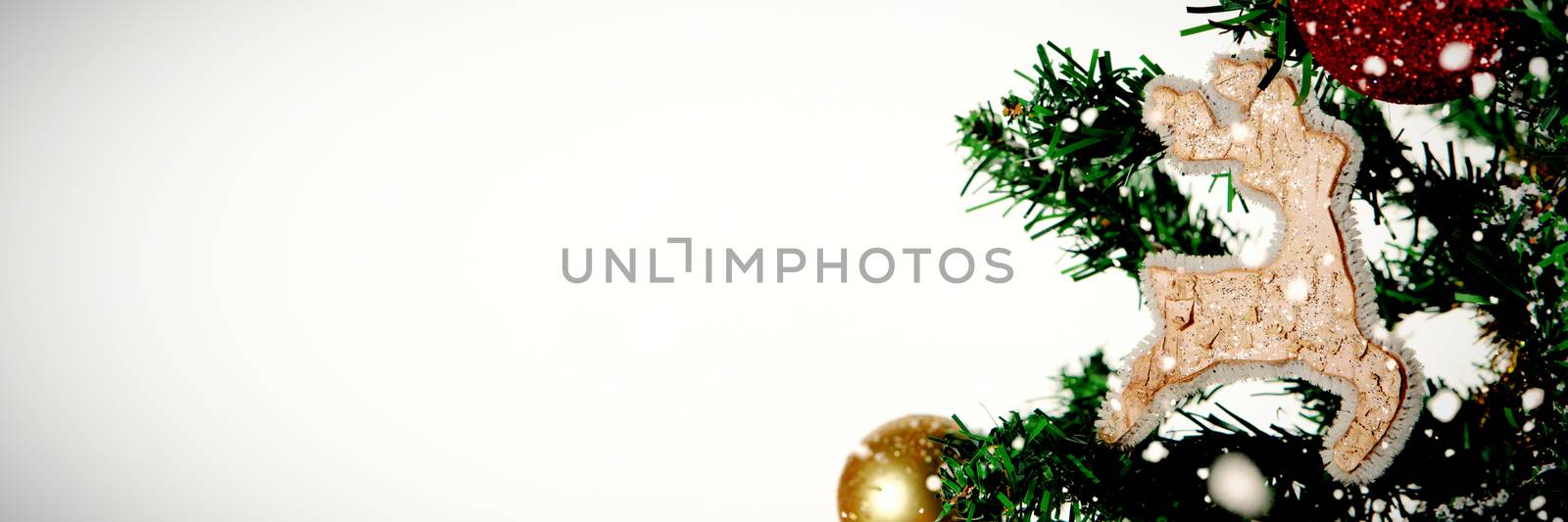 Snow falling against christmas ornaments hanging in tree with copy space