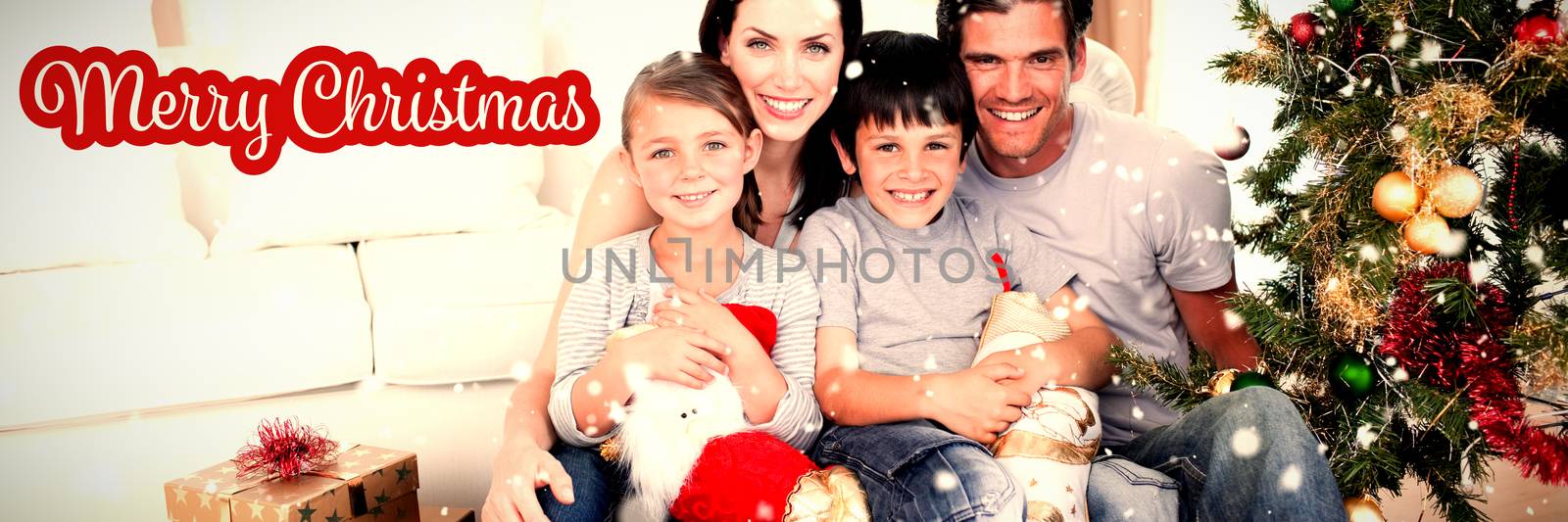 Happy family at Christmas time holding lots of presents against white and red greeting card