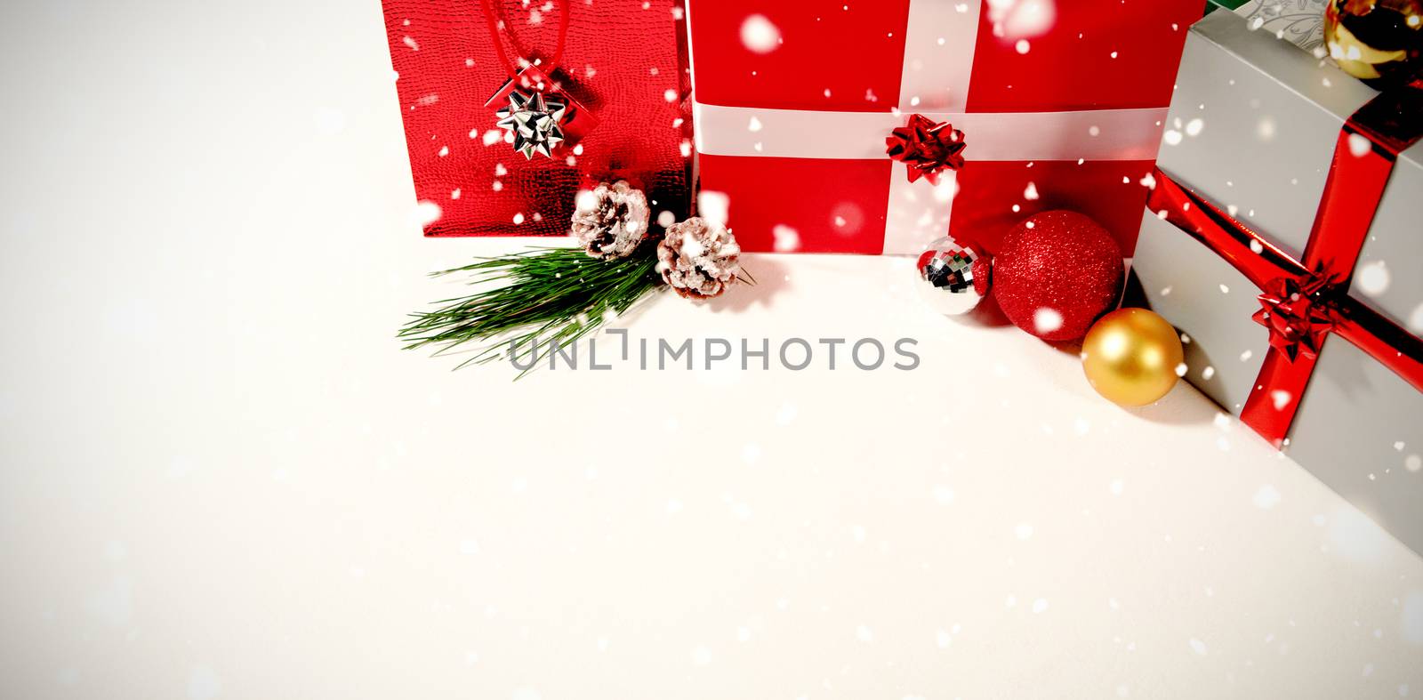 Snow falling against christmas gifts against white background