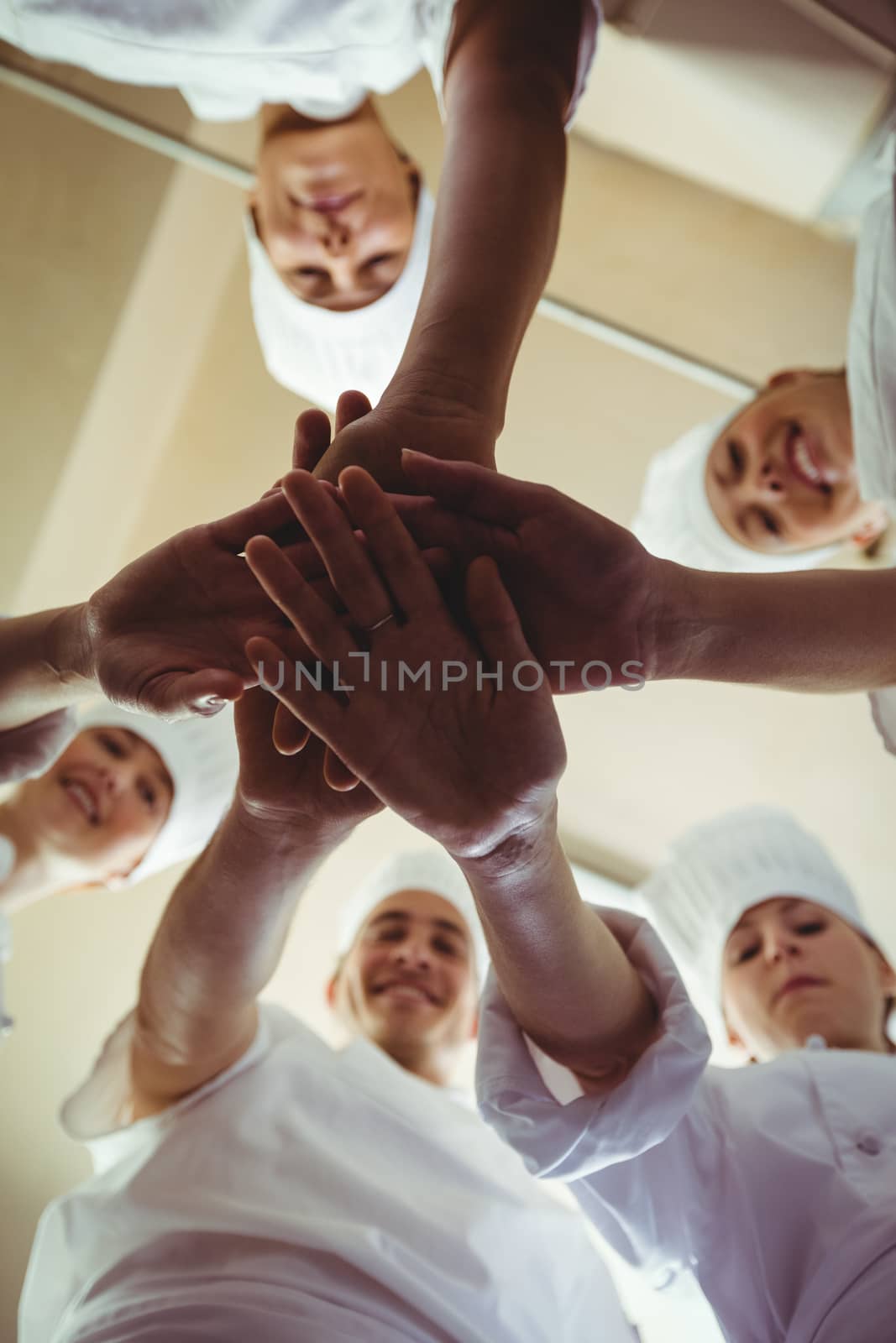 Group of chefs formig hands stack om kitchen at hotel