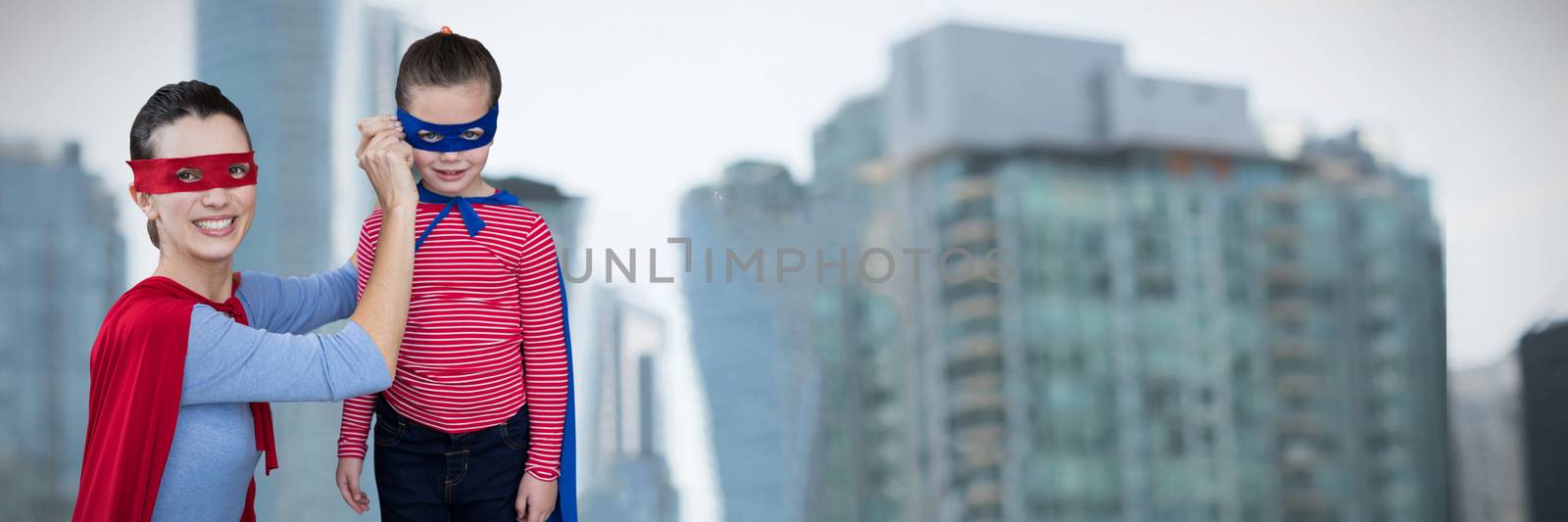 Mother and daughter pretending to be superhero against skyscrapers