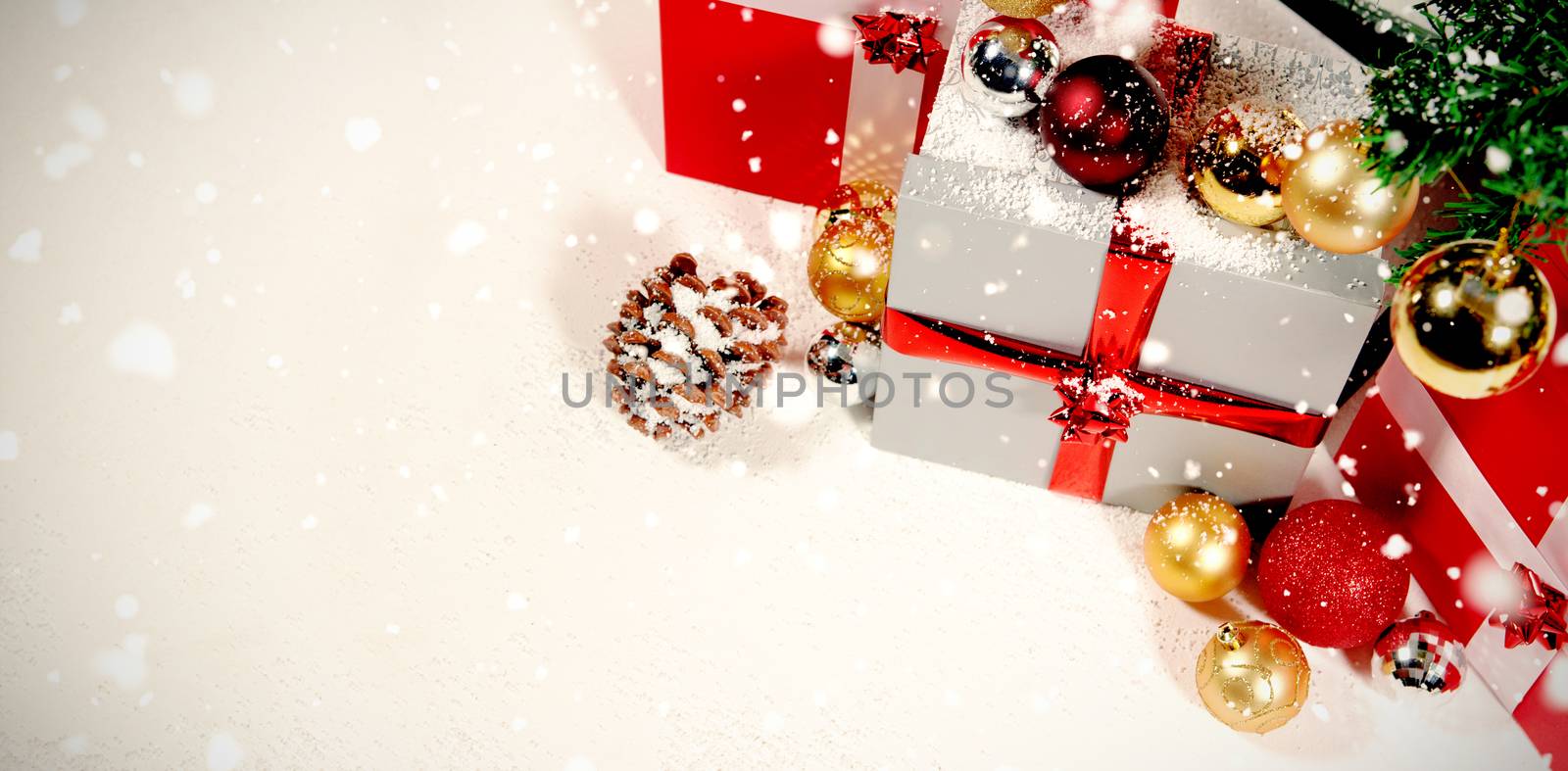 Snow falling against christmas gifts and decoration against white background