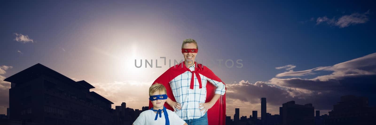 Mother and son pretending to be superhero against picture of city by sunrise