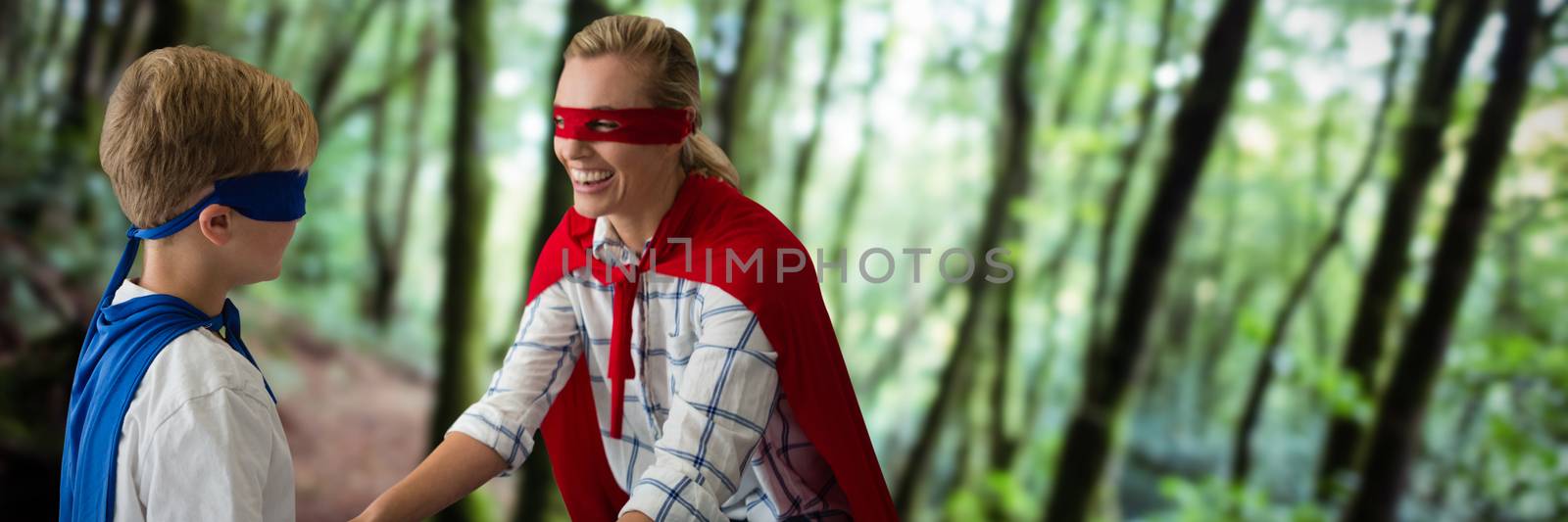 Mother and son pretending to be superhero against tree trunks in forest