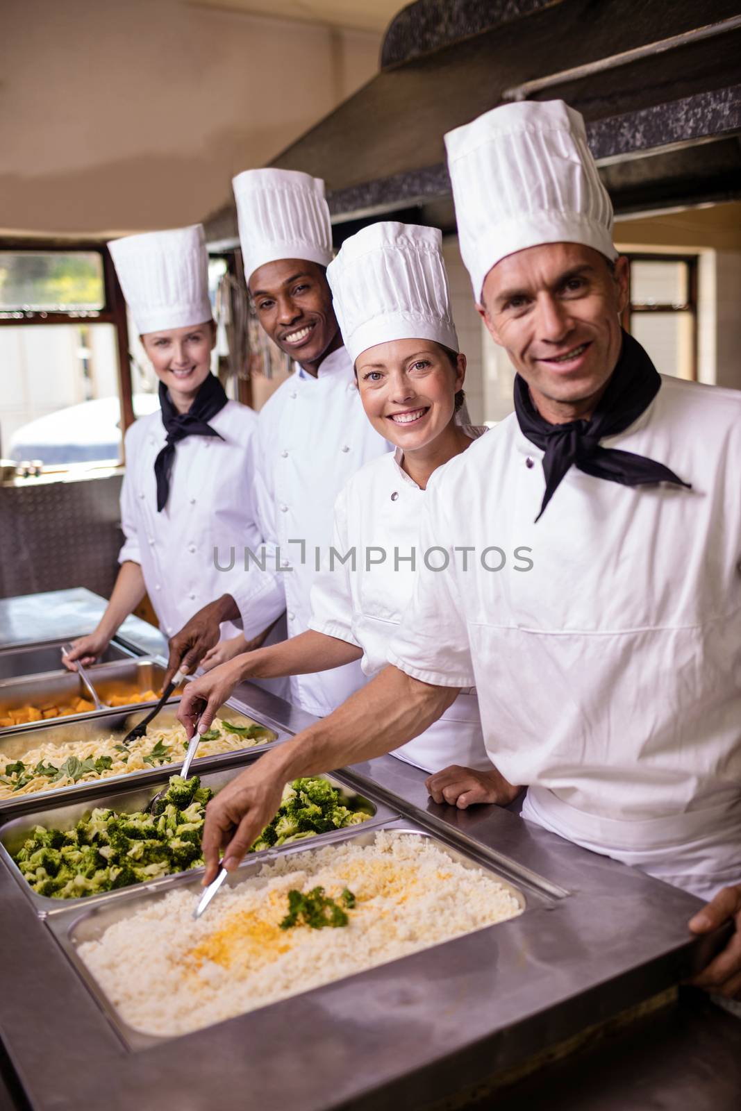 Group of chefs stirring prepard foods in kitchen at hotel