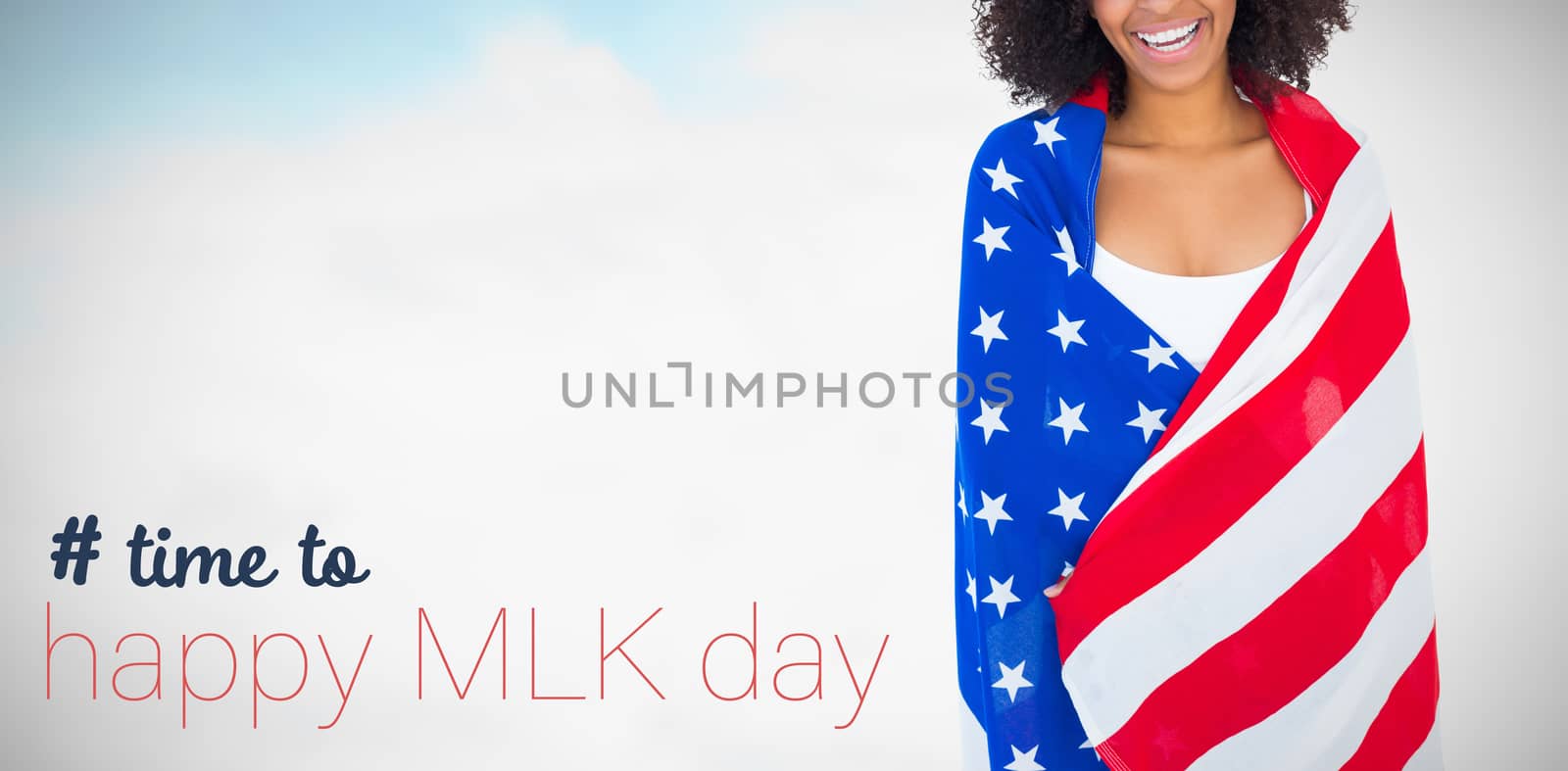 Pretty girl wrapped in american flag smiling at camera against blue sky with clouds 