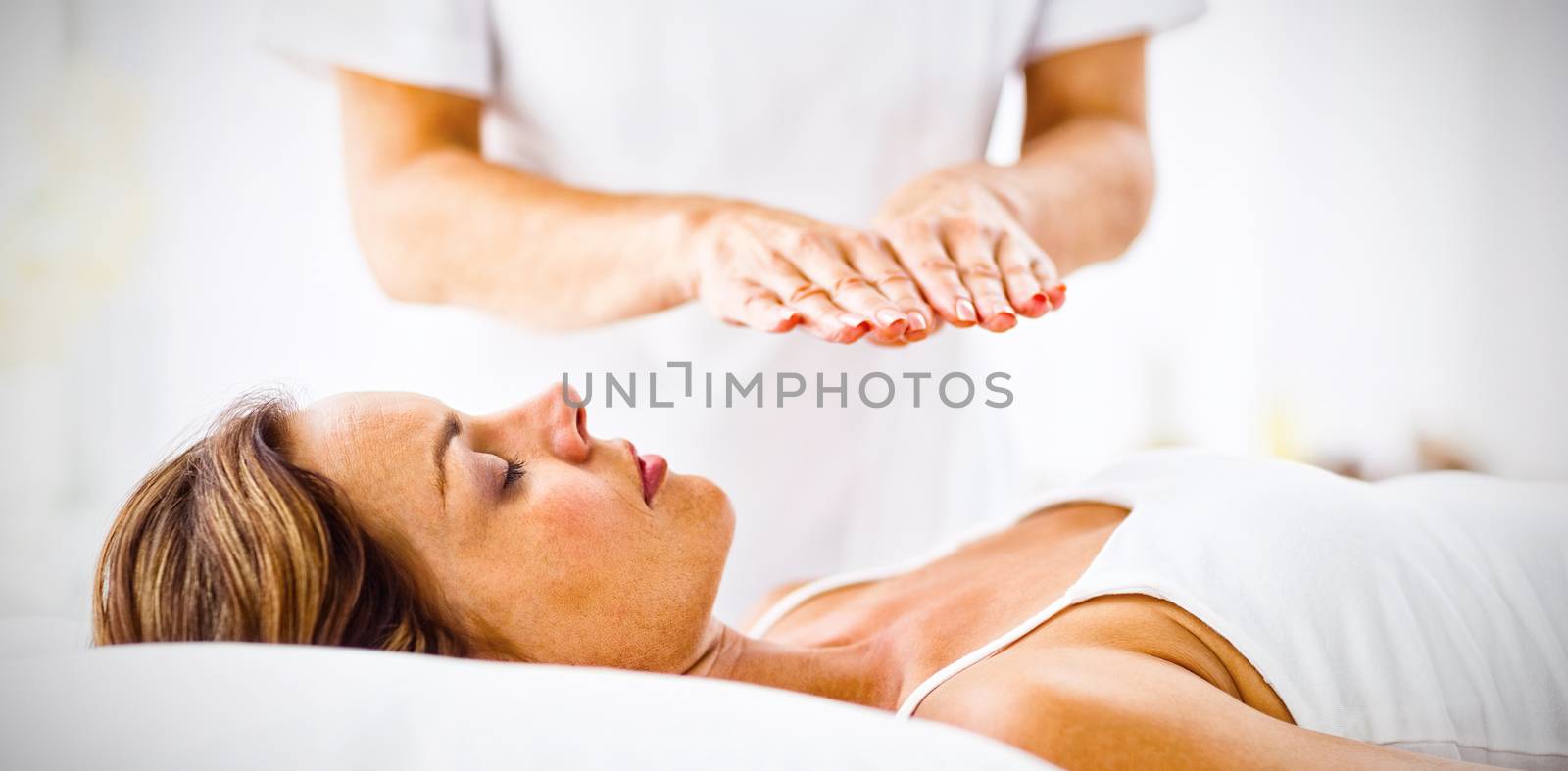 Young woman receiving reiki treatment at spa