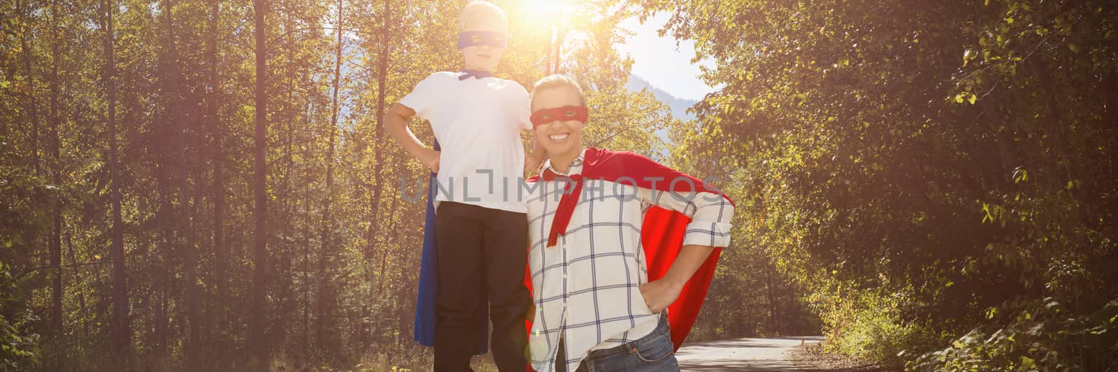 Mother and son pretending to be superhero against road passing through forest