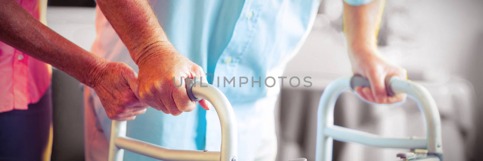 Mid section of senior woman helping senior man to walk with walker